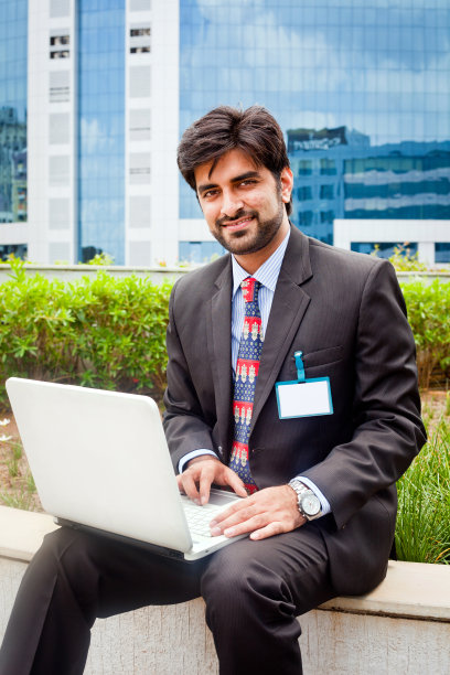 年轻的亚洲印度商人坐在户外使用笔记本电脑图片下载