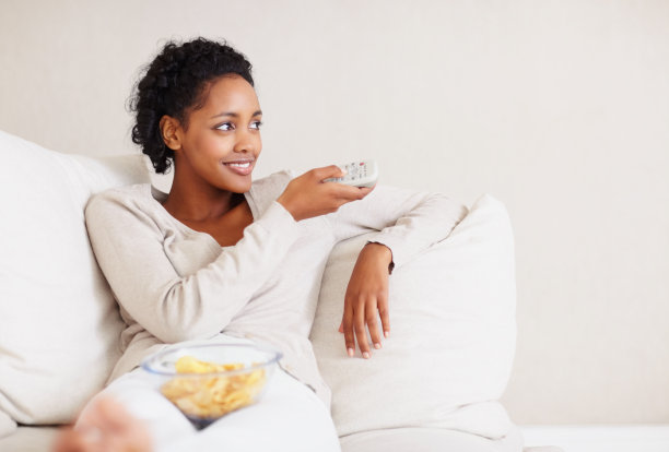 可爱的非洲女士用遥控器看电视图片下载