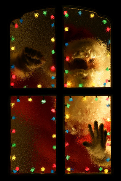 圣诞老人透过被灯光照亮的窗户向外看图片下载