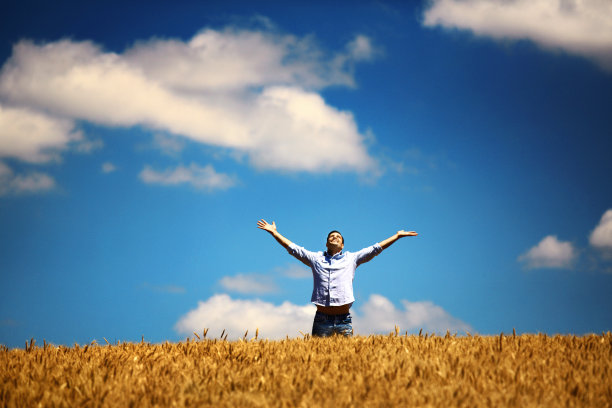 一个人举着手臂站在麦田里。图片下载