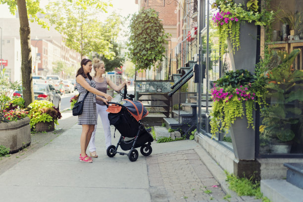 都市妈妈推着婴儿车和朋友逛街。图片下载