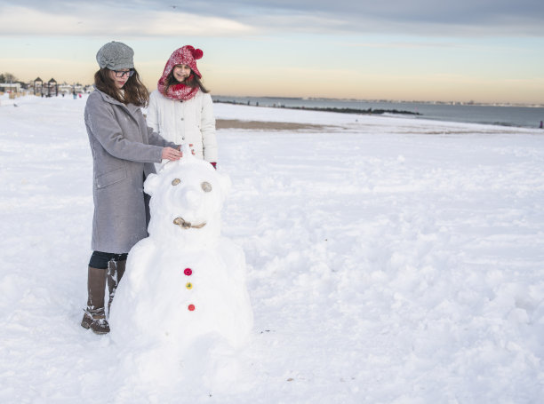 两个少女朋友在海滩上堆雪人素材图片