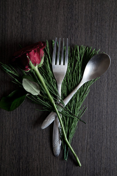 木桌上放着带植物的红玫瑰和勺子图片下载