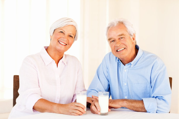老夫妇拿着牛奶坐在餐桌上图片下载