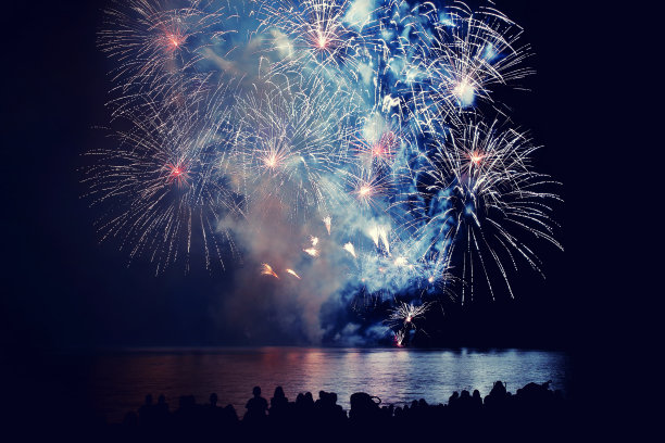 美丽的大型多彩的烟花表演与辨认不出的人群观看素材图片