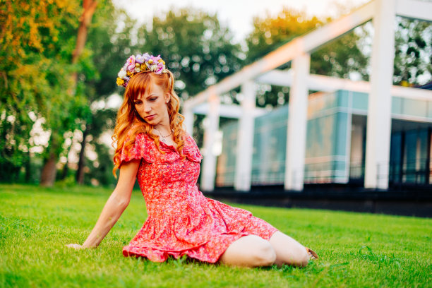 美丽的女人在夏天的下午在公园的绿色草地上放松。图片下载