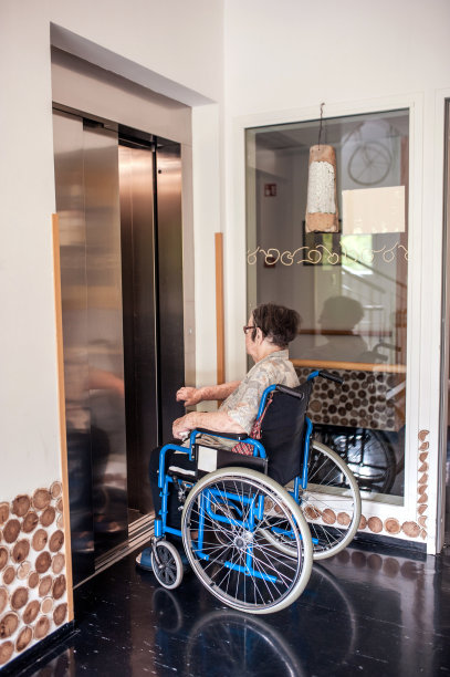 疗养院里坐轮椅进电梯的老年妇女图片下载