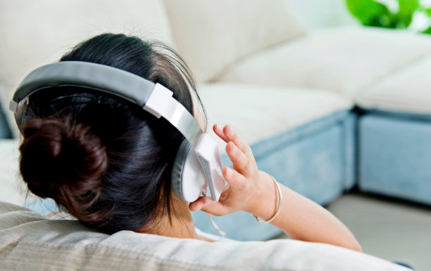 年轻女子坐在沙发上，戴着耳机图片下载