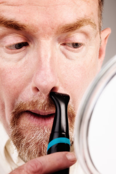 成熟的男人修剪着山羊胡，看着手镜图片下载