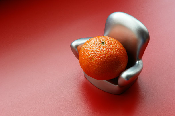 放松疲惫的橙色…倚在银扶手椅上;红色的背景图片下载