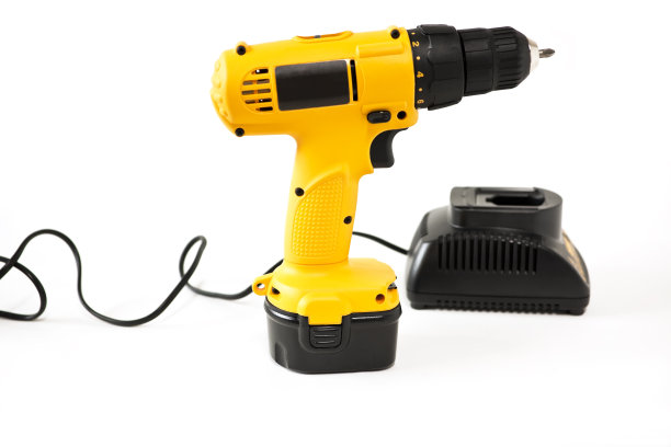 黄色和黑色钻机与电池充电器在其背景。图片下载
