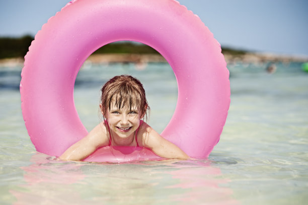 小女孩和粉红色的游泳管在海里。图片下载