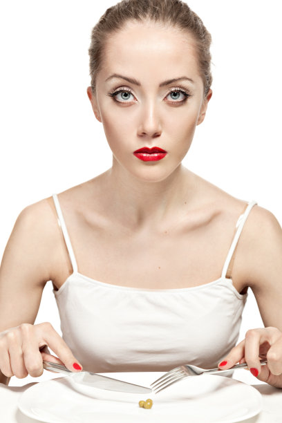 一个不开心的女孩看着盘子里的豌豆。图片下载