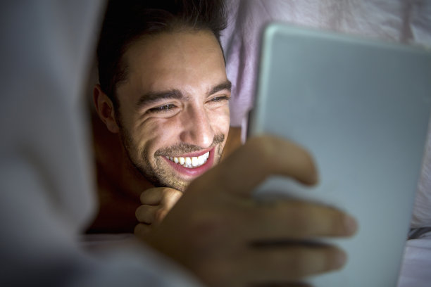 快乐的人在家里的毯子下使用数码电脑图片下载