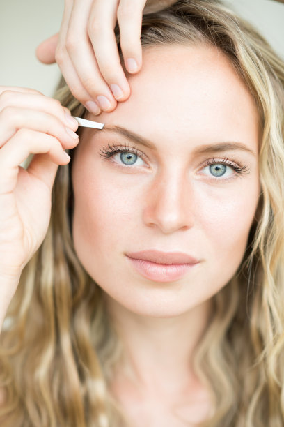 美丽的女人拔她的眉毛用镊子图片下载