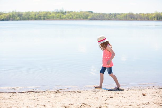 在海滩上沿着海岸线散步的女孩的侧视图图片下载