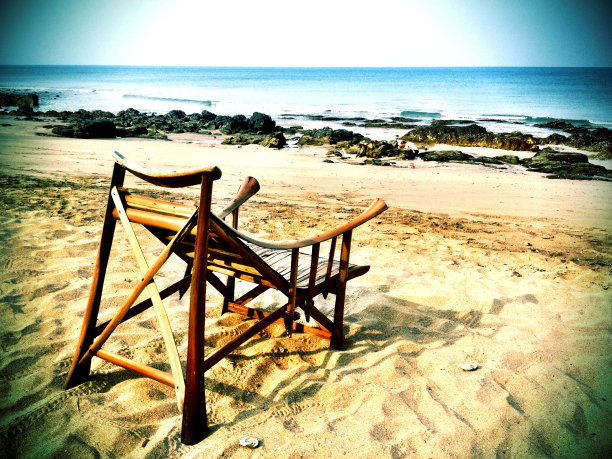 移动美学:在空旷的热带海滩上，吸引人的木椅面向大海。图片下载