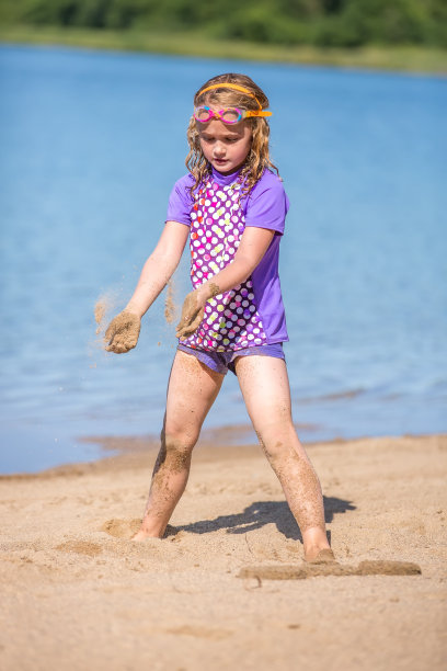 女孩在沙滩上玩沙子在夏天的一天图片下载