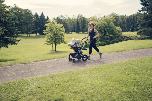 新妈妈在公园里推着婴儿车慢跑。图片下载