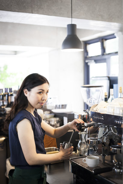亚洲女招待正在用咖啡机图片下载