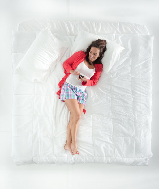 以上的妇女使用手机和躺在床上的观点图片下载