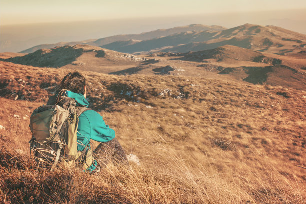 女孩徒步旅行者坐在美丽的山上图片下载