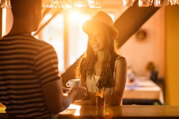 微笑的女人在吧台点一杯咖啡。图片下载