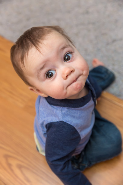 小男孩坐在地板上，向上看图片下载