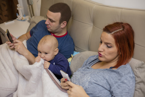 父母用手机白色躺在床上的婴儿图片下载