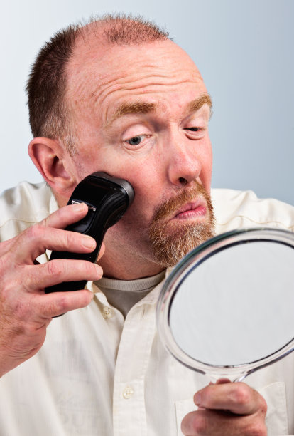 刮胡子的男人看着镜子，做着鬼脸图片下载