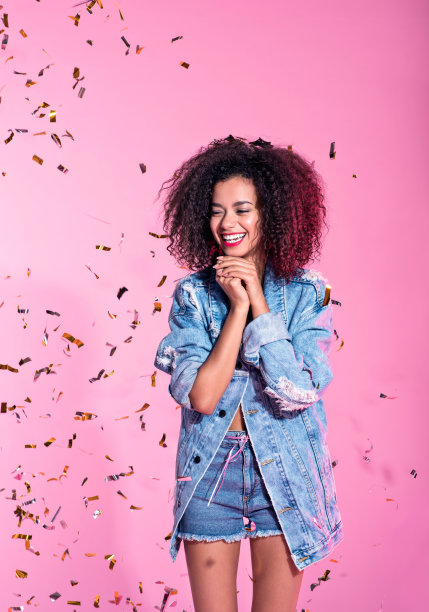 快乐的年轻黑人妇女的肖像在五彩纸屑中素材图片