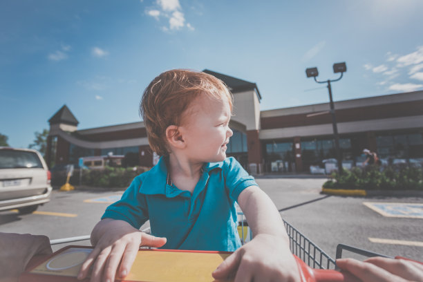 蹒跚学步的小男孩坐在超市的购物车里图片下载