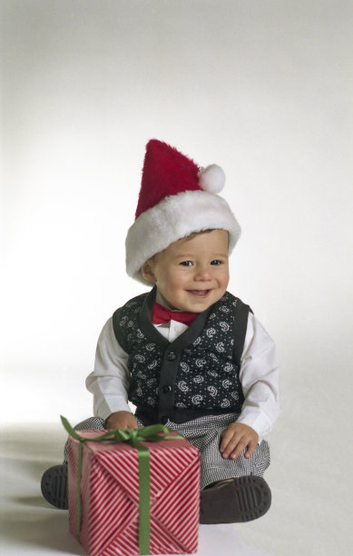 婴儿男孩穿好衣服，带着包裹好的礼物图片下载