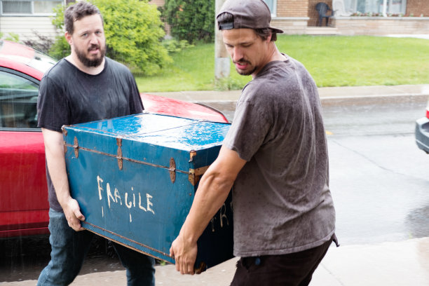 两个学生在一个下雨天搬家具图片下载