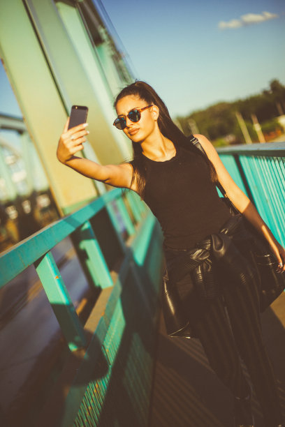 美丽的女孩在桥上散步和自拍图片下载