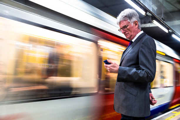 高级商人在等火车，看着他的手机图片下载