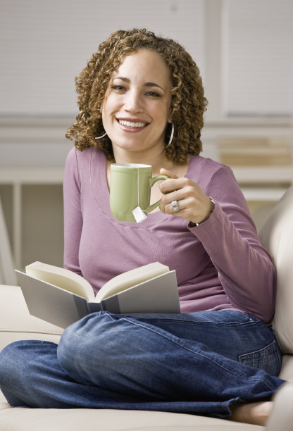 悠闲的女人在客厅里喝茶，享受着读书图片下载