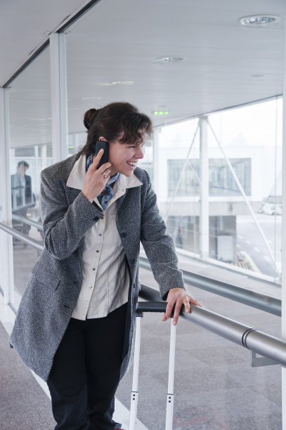 女游客在机场打电话时大笑。图片下载