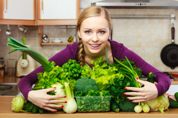 微笑的女人在厨房和绿色蔬菜图片下载