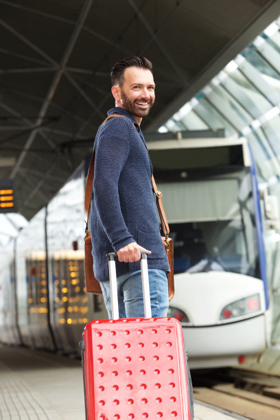 一个拿着箱子站在站台上的男人图片下载