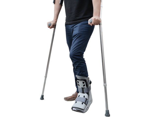 腿部骨折的男子戴着护膝和拐杖图片下载