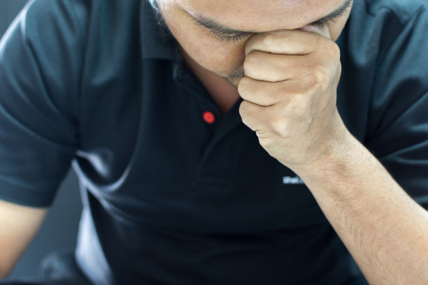 亚洲男人留着短发，留着胡子，穿着黑色polo衫，有一种思考的姿态图片下载