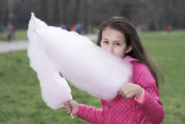 在公园里吃棉花糖的披发女孩图片下载