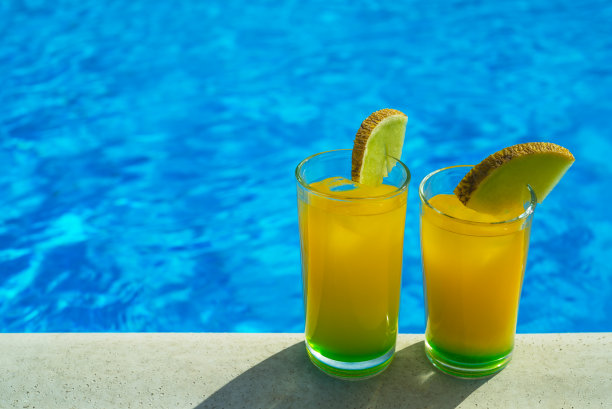 泳池前装有黄绿色鸡尾酒的玻璃杯图片下载