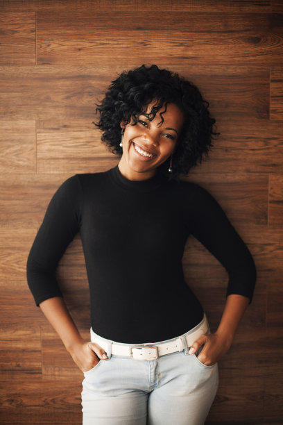 在木墙上微笑的非裔美国妇女。图片下载