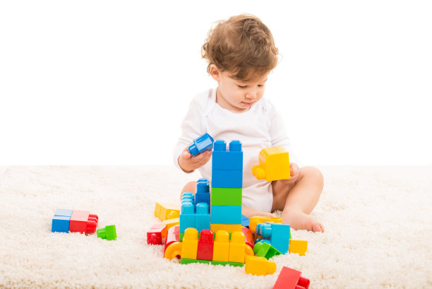 蹒跚学步的小男孩在地毯上玩耍图片下载