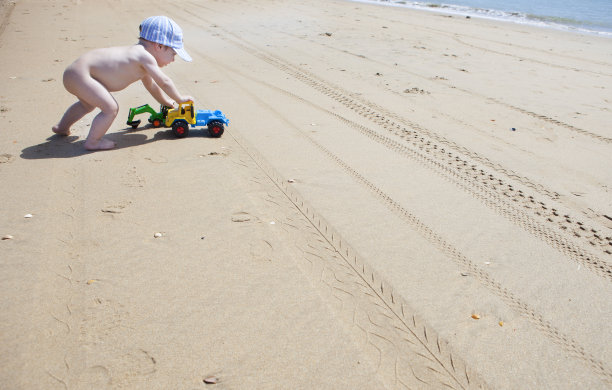 小男孩在沙滩上推他的玩具图片下载
