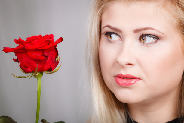 女人捧着红玫瑰，近脸愁容图片下载