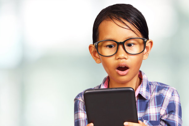 年轻女孩看着她的平板电脑感到震惊图片下载