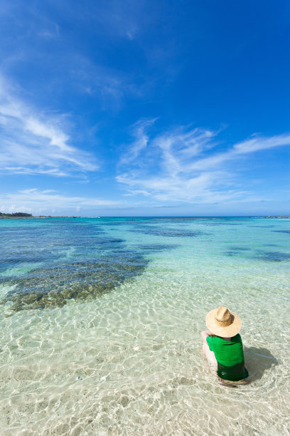 女人坐在浅水清澈的热带海滩，日本图片下载